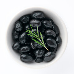 Delicious black olives in plate with olive tree sprig decoration isolated on white background top view for your design. Healthy eating, healthy fats for humans. Organic vegetable