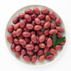 Delicious pink olives in plate with olive tree sprig decoration isolated on white background top view for your design. Healthy eating, healthy fats for humans. Organic vegetable