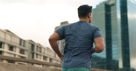 Back, running and a sports man in the city for cardio training to improve fitness for a marathon. Exercise, workout or health with a young runner or athlete in an urban town for a speed challenge