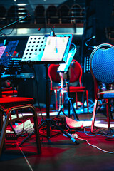 Musical music stand on stage. Scattered sheets of music on the floor