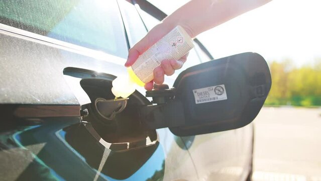 A man pours a diesel fuel additive into a car's fuel tank. Anti-freeze gel for diesel fuel, improving fuel quality and high cetane number of diesel. Slow motion