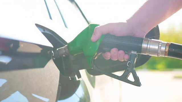 Fuel refueling nozzle in a car tank at a gas station. Tips for refueling your car with high-quality diesel. Diesel cetane number, freezing point. Refueling a car against the backdrop of sunset. Slow