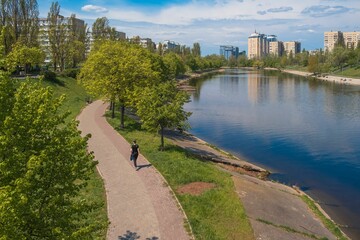 Woman on a pathway lined with lush greenery along a river