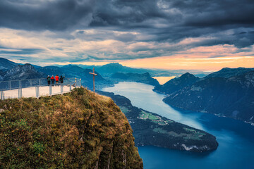 Fronalpstock with cross and tourist traveling on summit and moody sky overlooking Lake Lucerne at...