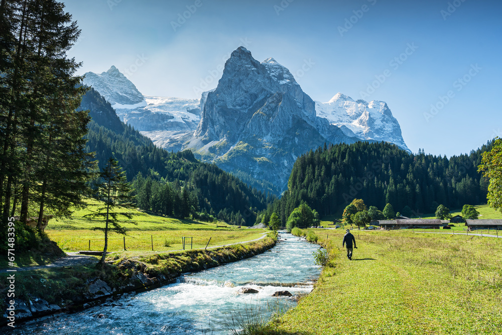 Wall mural view of rosenlaui with male tourist walking along reichenbach river and wetterhorn glacier mountain 