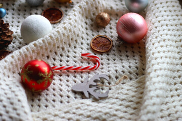 Various colorful Christmas ornaments, small presents and seasonal spices on white knitted blanket. Selective focus.