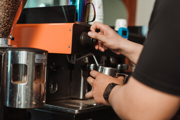 Barista steaming milk prepare whips milk to make latte coffee from coffee machine. process of making milk foam.