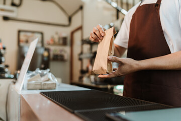 Waitress giving paper bag to customer at coffee shop. SME business coffee shop concept.