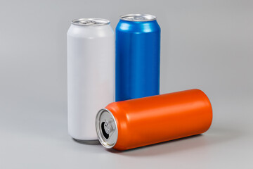Sealed and open varicolored beverage cans on a gray background