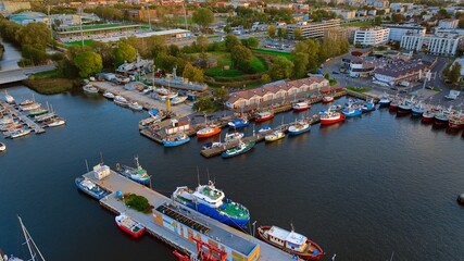 A breathtaking aerial drone photo of Kołobrzeg's marina in Poland captures a picturesque scene. The view showcases a multitude of yachts, sailboats, fishing boats and ships. - obrazy, fototapety, plakaty