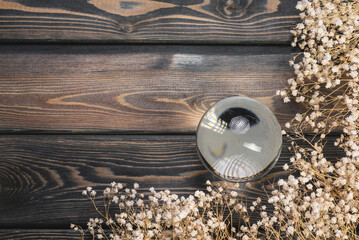 Magic crystal ball and dried flowers on the flat lay table background.