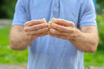 Man's hand holds mini bread, snack and fast food concept. Selective focus on hands with blurred background