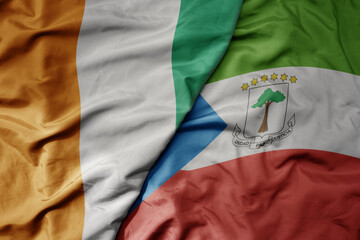 big waving national colorful flag of cote divoire and national flag of equatorial guinea .