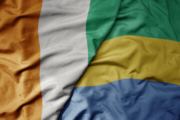 Fototapeta premium big waving national colorful flag of cote divoire and national flag of gabon .