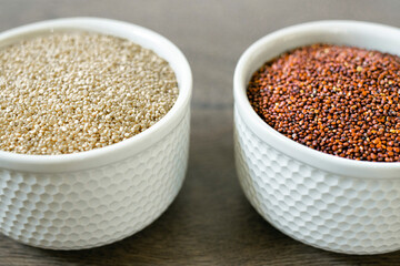 Red and white quinoa on the two white plates on the wooden background. Healthy food and nutrition concept. Safe, ecological, and healthy products