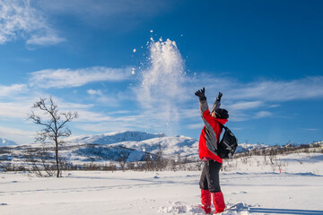 Sporty person in red sport jacket enjoys snow and breathtaking Norwegian landscape. Sunny winter...