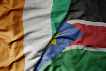 big waving national colorful flag of cote divoire and national flag of south sudan .