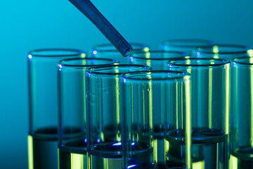 Close up of laboratory test tubes and pipette with copy space on blue background