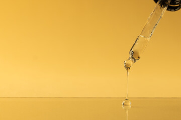 Close up of pipette with drop and copy space on yellow background