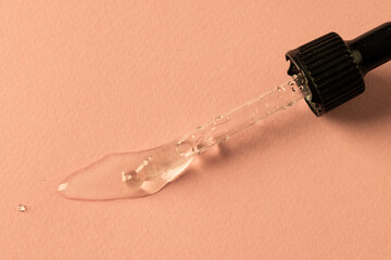 Close up of pipette with drop and copy space on pink background