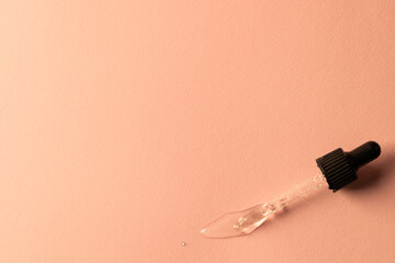Close up of pipette with drop and copy space on pink background