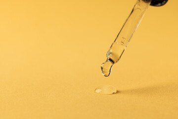 Close up of pipette with drop and copy space on yellow background