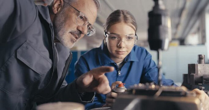 Instructor showing apprentice to cool metal drill in workshop