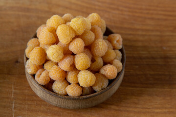 Yellow raspberries in a wooden bowl on the table. Summer berries background. Vitamin food, berry harvest. Healthy nutrition.