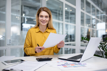 Portrait happy successful woman financier doing paperwork, businesswoman holding papers, documents, contracts and reports in hand, smiling joyfully, satisfied working with laptop, using calculator - obrazy, fototapety, plakaty