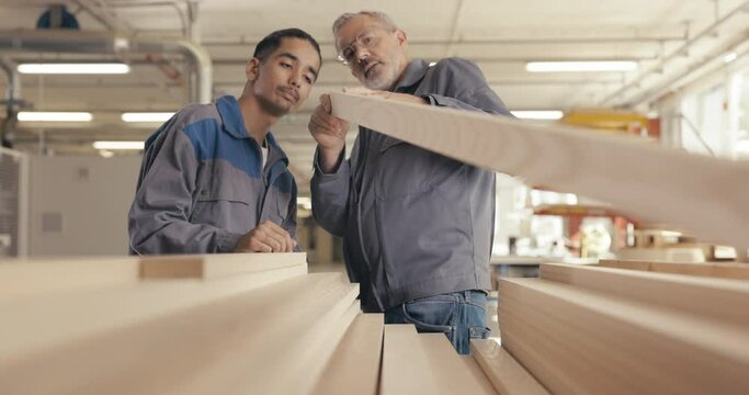 Apprentice and instructor examine wood panel in workshop