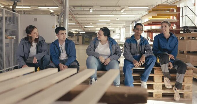 Fellow carpentry apprentices sitting on pallet in the wood workshop