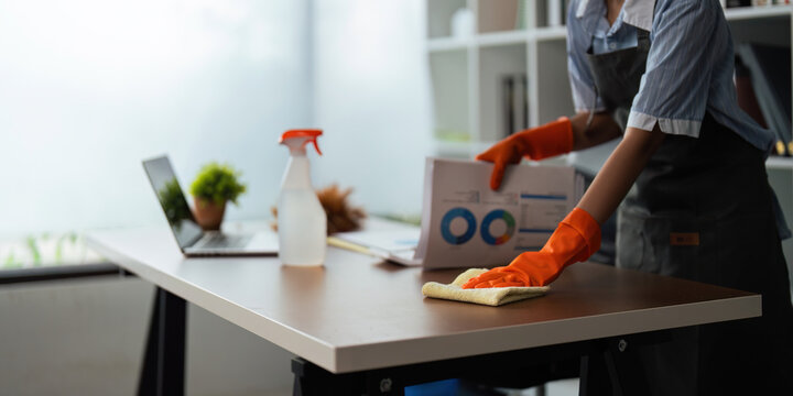 Asian Woman Cleaning In Work Room At Home. Young Woman Housekeeper Cleaner Use A Cloth To Wipe Equipment For Working. Concept Housekeeping Housework Cleaning