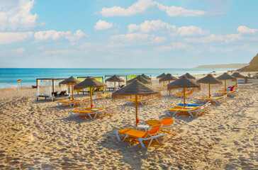 rows of deck chairs and umbrellas on sandy beach