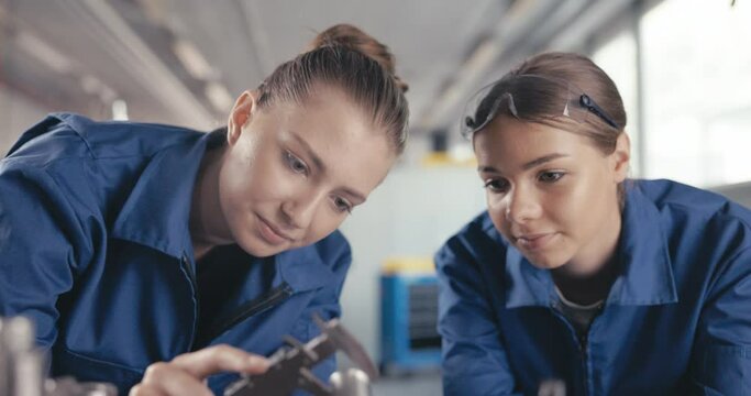 Apprentices measuring drill parts and bits with caliper in workshop