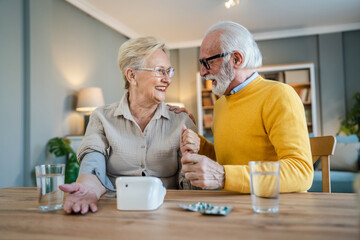 senior couple at home woman check blood pressure husband sit beside