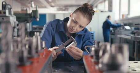 Apprentice measuring metal bolt with caliper in workshop