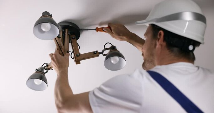 handyman services. electrician installing ceiling light lamp at home