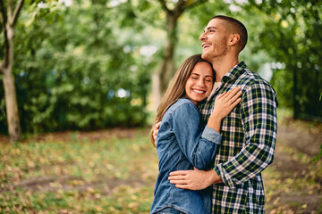 Fototapeta premium A beautiful couple being in the nature, hugging each other, looking happy.
