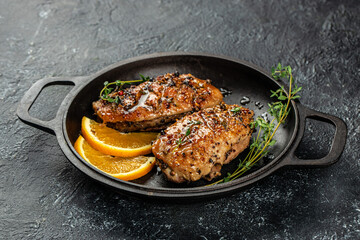 roasted duck meat steak with oranges and thyme in a pan. on a dark background. top view. copy space