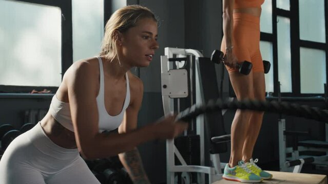 Women exercise on stepper and use battle rope at workouts