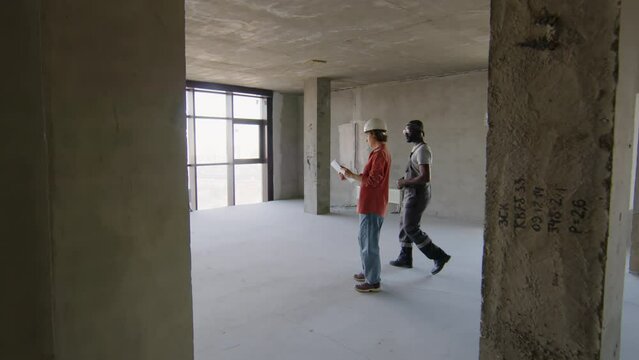 Zoom in shot of construction workers looking at plan of room