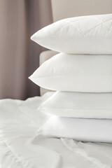 Different types of white bed pillows on a white bed. Pillow menu. Cushions. Home textile
