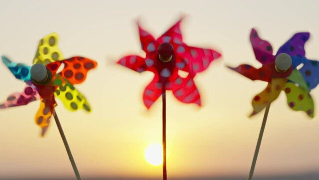 Silhouette Three plastic pinwheel rotates color, windmill with blowing wind sunset sky of sunny day slow motion. Descending bright disk of sun beyond horizon on field wheat sun. Nature. Emotions Relax