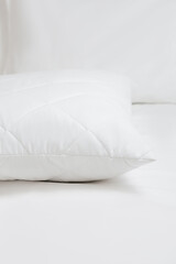 Fototapeta na wymiar White quilted pillow on a white bedding white background. Cushion. Home textile. Close up photo, top view