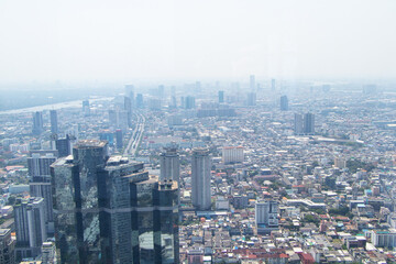 Fototapeta na wymiar Scenery aerial view on top of buildings in town Bangkok, Thailand city with air cloudy by fog or air pollution in evening with hotels and office towers . White sky was blurred with bright sunlight.