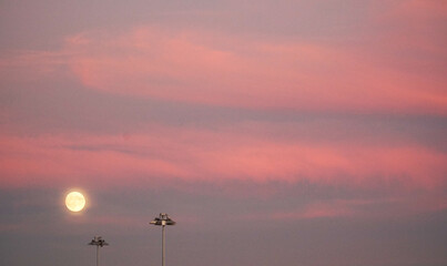 The rise of the moon in the pink sky