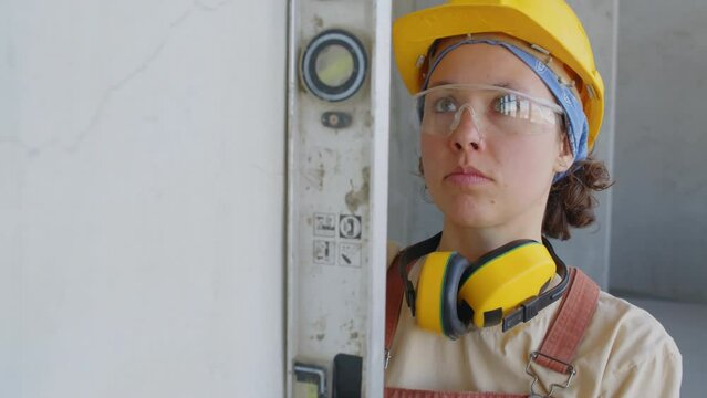 Female builder checking surface of wall at construction site