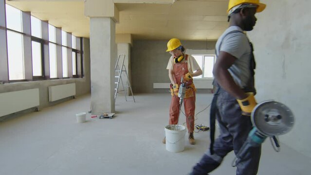 Female builder working with cement in container at construction site