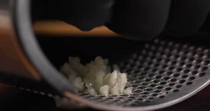 Crushing a clove of garlic using a modern garlic press
