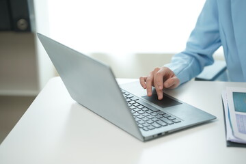 Asian and African businesswoman using laptop and drinking coffee in modern office